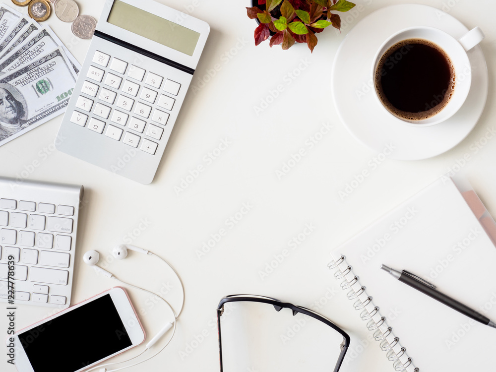 top view of accounting concept with keyboard, smartphone, notebook, coffee cup, calculator and money on white table background. top view of accounting concept with keyboard, smartphone, notebook, coffee cup, calculator and money on white table background.