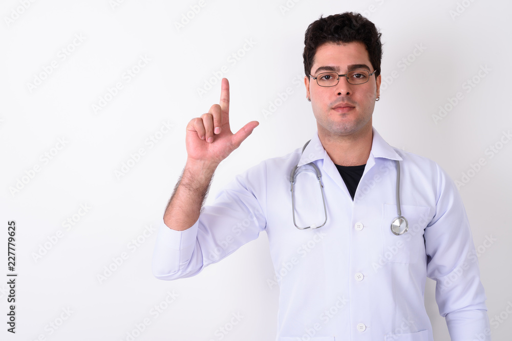 Young handsome Persian man doctor wearing eyeglasses against whi Young handsome Persian man doctor wearing eyeglasses against whi