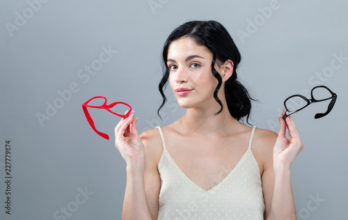 Young woman comparing two eye glasses on a gray background photo