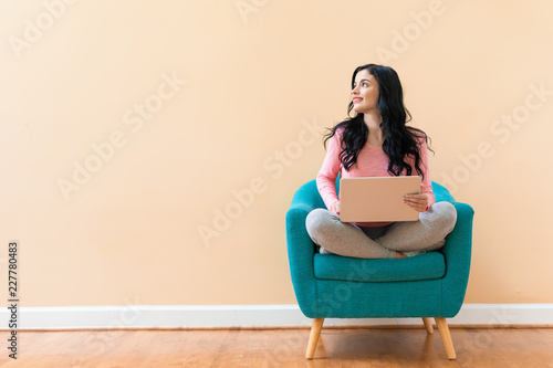 Young woman using her laptop on a blue chair