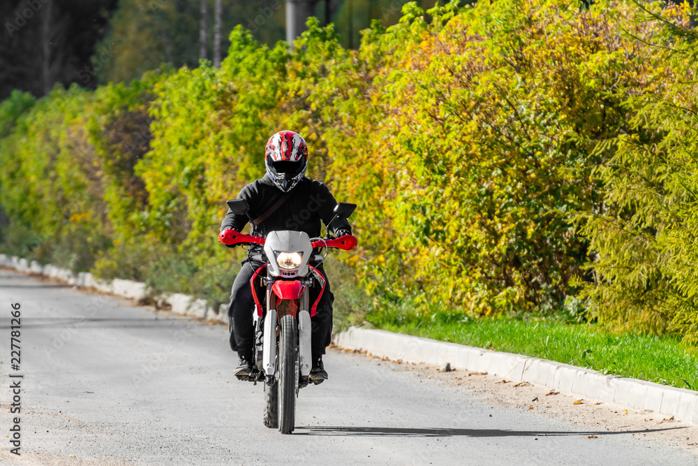 A man on a cross-country motorcycle riding along an asphalt road A man on a cross-country motorcycle riding along an asphalt road