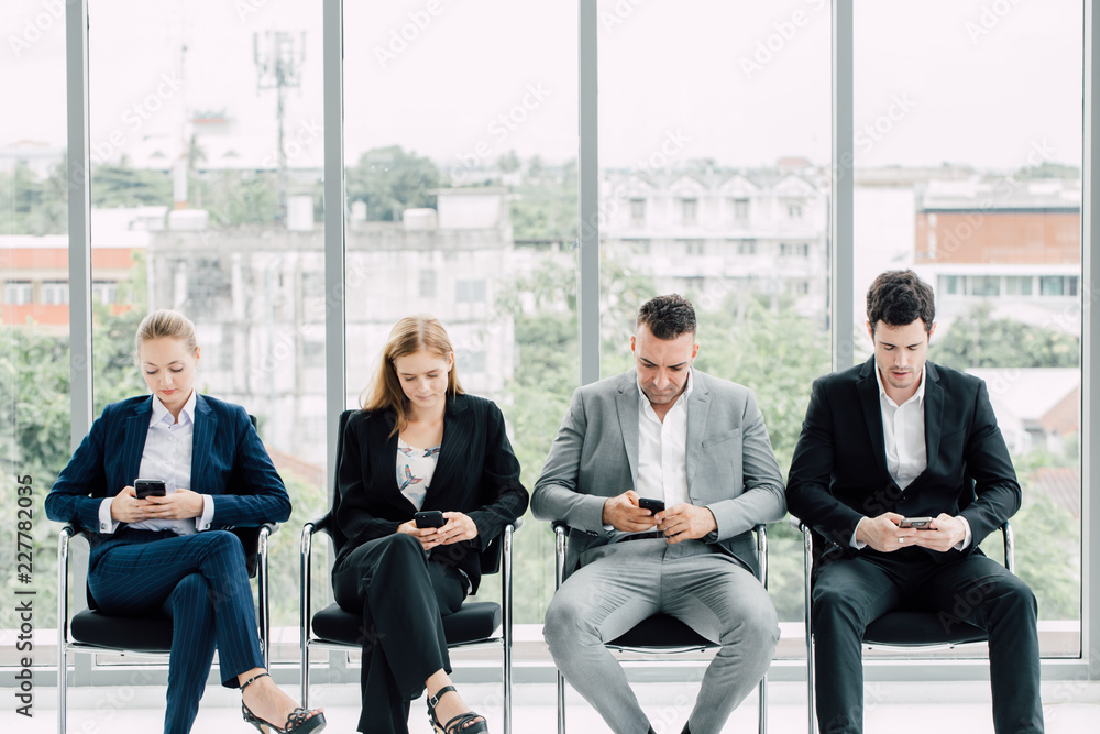 Group of business people sitting chair and using their mobile phones, ignoring work and social networking. Group of business people sitting chair and using their mobile phones, ignoring work and social networking.