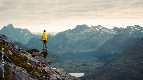 Naklejka Przygód człowiek stoi na szczycie góry i podziwiając piękny widok podczas wibrującego zachodu słońca. Pięknej natury Norwegia naturalna krajobrazowa powietrzna fotografia
