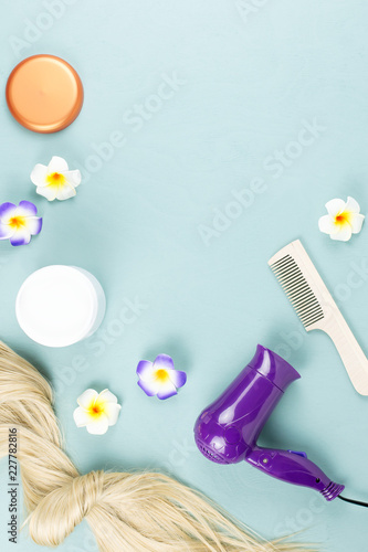 Hairdressing tools, nourishing mask and hair extensions on blue wooden background. Hair care concept flat lay