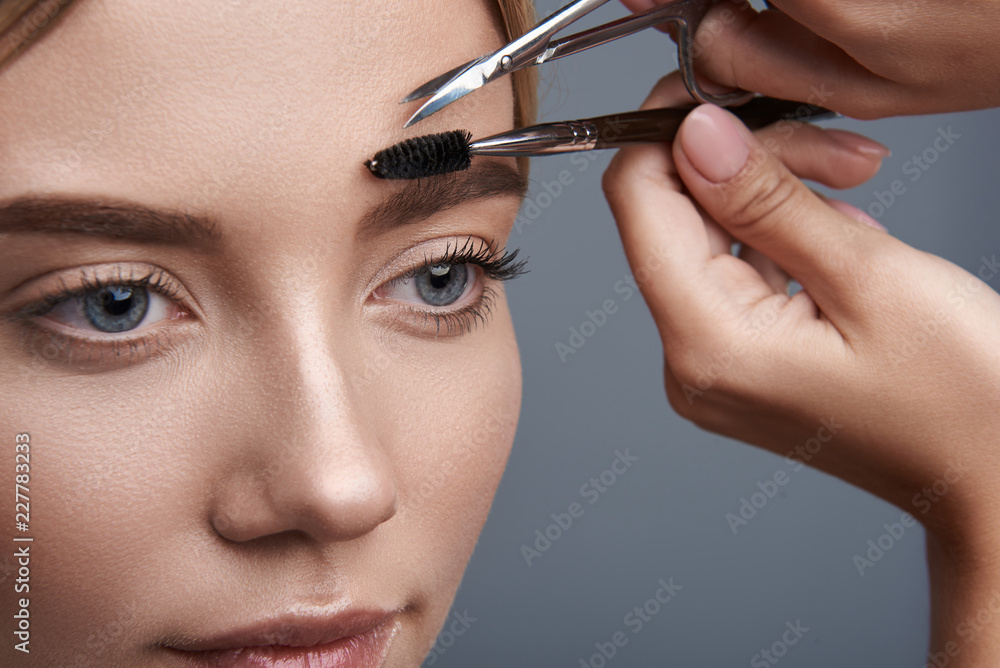 Peaceful beautiful woman visiting her cosmetologist and having her eyebrows cut and shaped