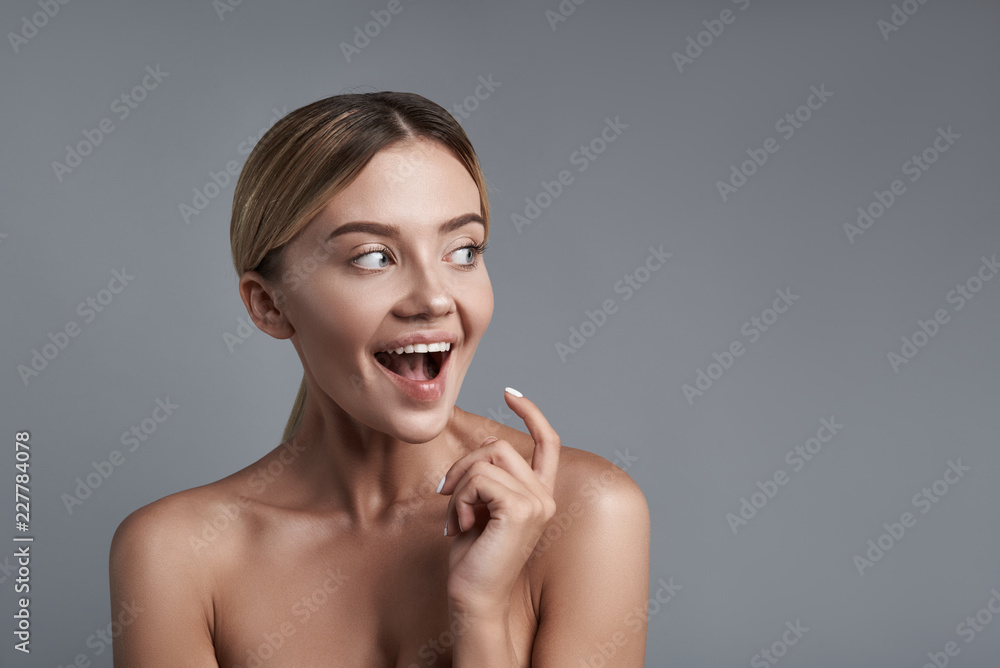 Excitement. Emotional young lady sitting with bare shoulders and opening her mouth while being excited Excitement. Emotional young lady sitting with bare shoulders and opening her mouth while being excited