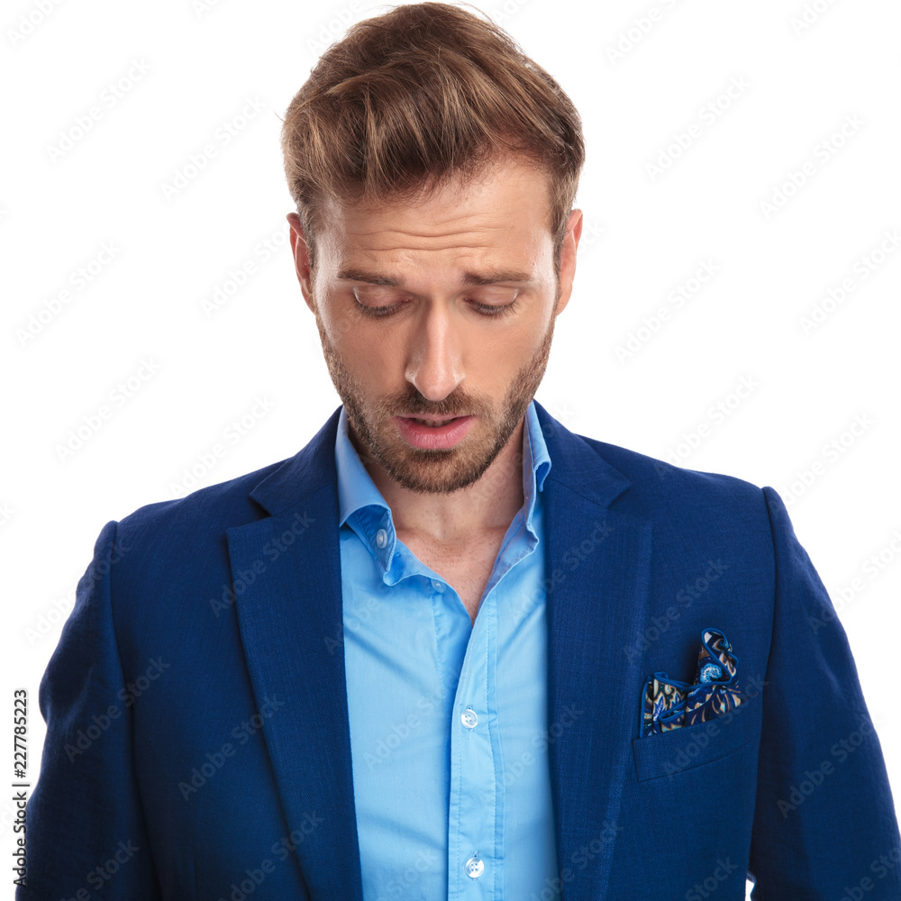shocked young smart casual man looks down shocked young smart casual man looks down