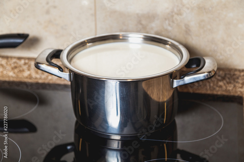 saucepan with milk stands on black electric stove