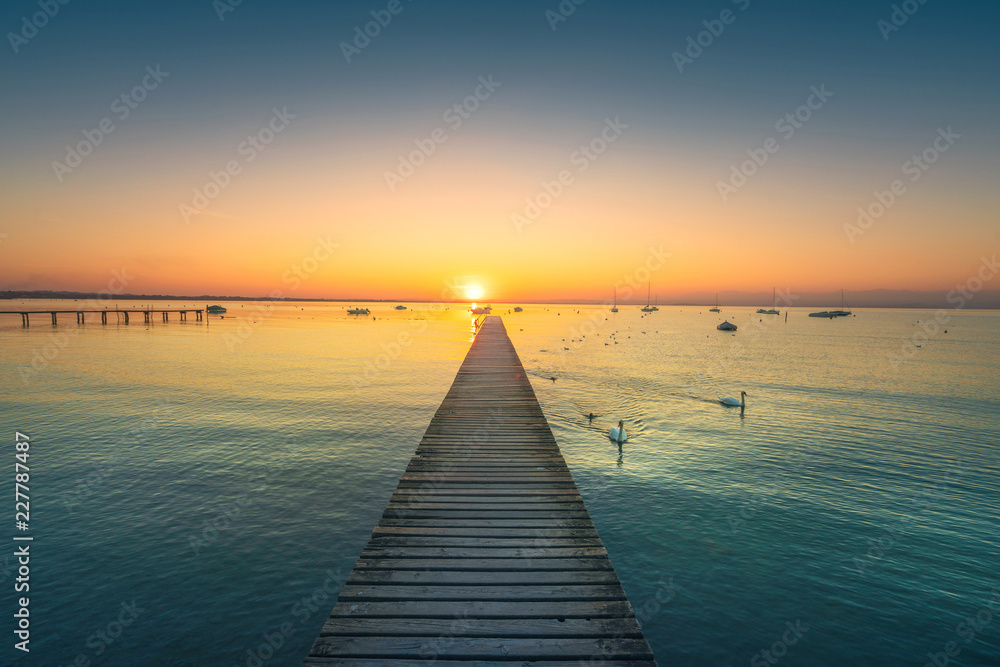 Garda lake, swans and jetty, sunset view from Pacengo Lazise. Italy