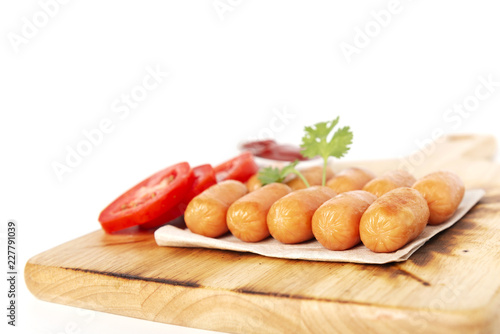 Fried sausages and fresh tomato, ketchup, coriander on the wood plate, isolated white background.