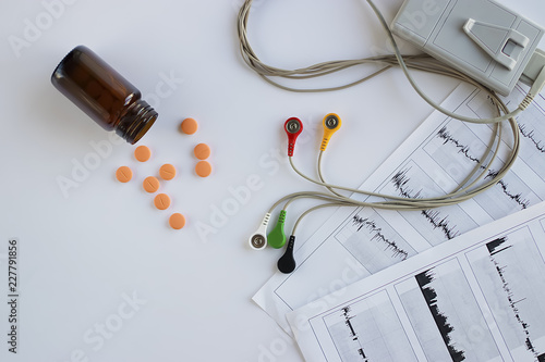 Device of holter monitoring and pills on white background. Concept of diagnosis and treatment of cardiovascular diseases.