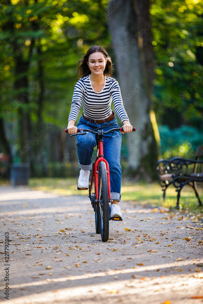 Fototapeta premium Urban biking - woman riding bike in city park