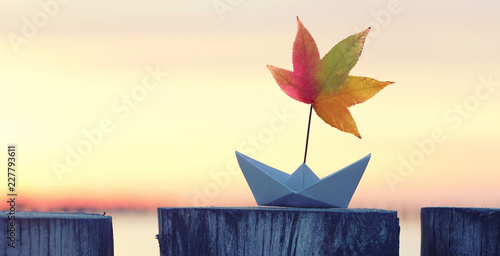 Fototapeta Naklejka Na Ścianę i Meble -  Papierboot mit bunten Laubblatt als Segel - Herbst