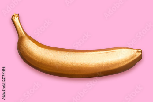 Golden metallic banana on a pink background. A modern creative concept. Contemporary art