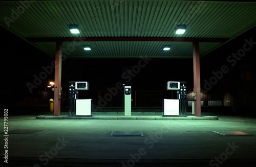 Dunkle, grün beleuchtete Tankstelle bei Nacht im Industriegebiet photo