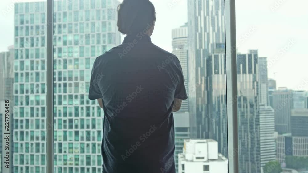Young businessman admire view from the window in business apartment. 3840x2160 Young businessman admire view from the window in business apartment. 3840x2160