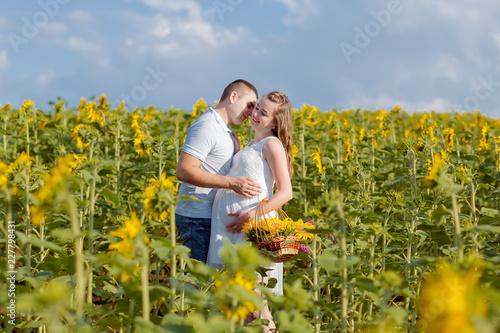 Happy pregnant couple in nature. sunflower in the field