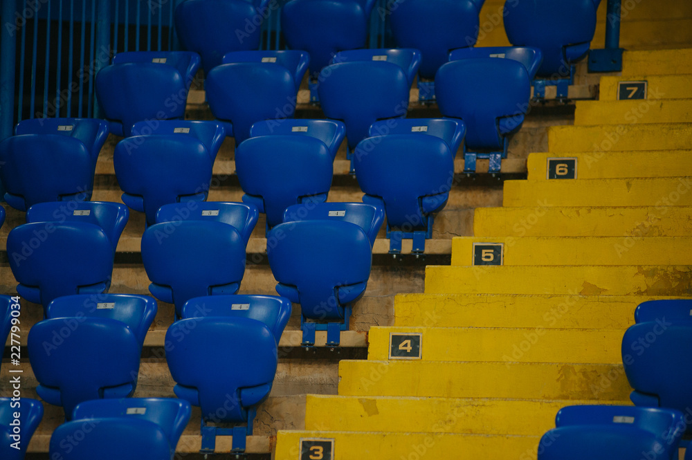 Obraz premium Niebieskie puste miejsca na stadionie piłkarskim. Żółte schody z kilkoma sektorami.