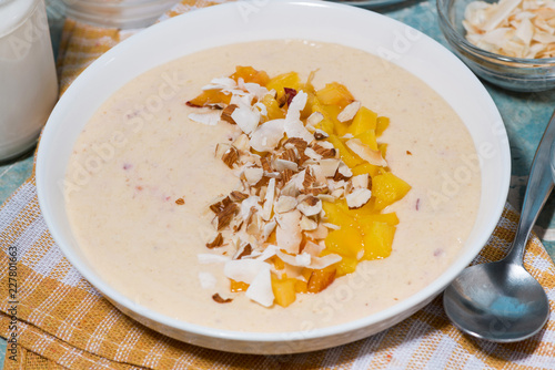 smoothie bowl with mango, coconut and nuts, closeup