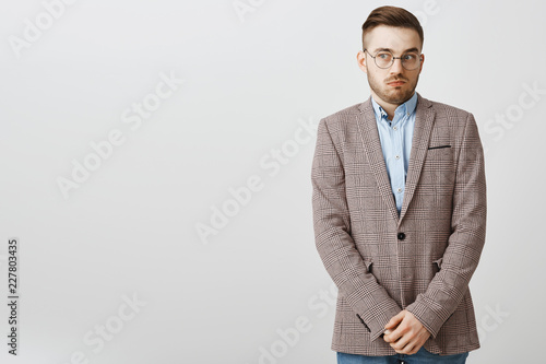 Intense worried european male employee feeling awkward and confused making mistake being scolded by boss feeling discomfort being in uncomfortable situation holding hands near pants and gazing aside photo