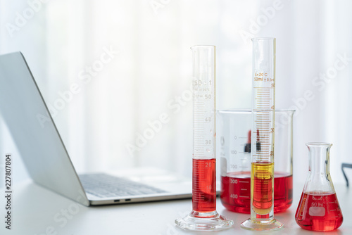 Scientist working desk with chemistry test tube and laptop in laboratory