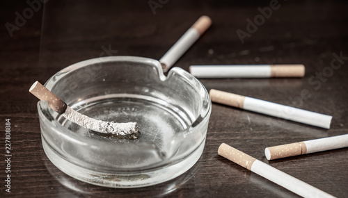 A glimmering cigarette burns in an ashtray on a table photo