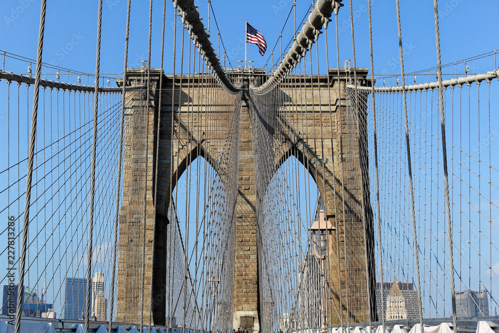 Naklejka premium New York, USA - November 22, 2010: The historic Brooklyn Bridge in New York City with US flag