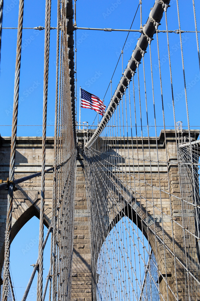 Fototapeta premium New York, USA - November 22, 2010: The historic Brooklyn Bridge in New York City with US flag