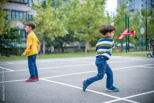 Wallpaper Mural Happy two brother kids playing with toy airplane against blue summer sky background. Torontodigital.ca