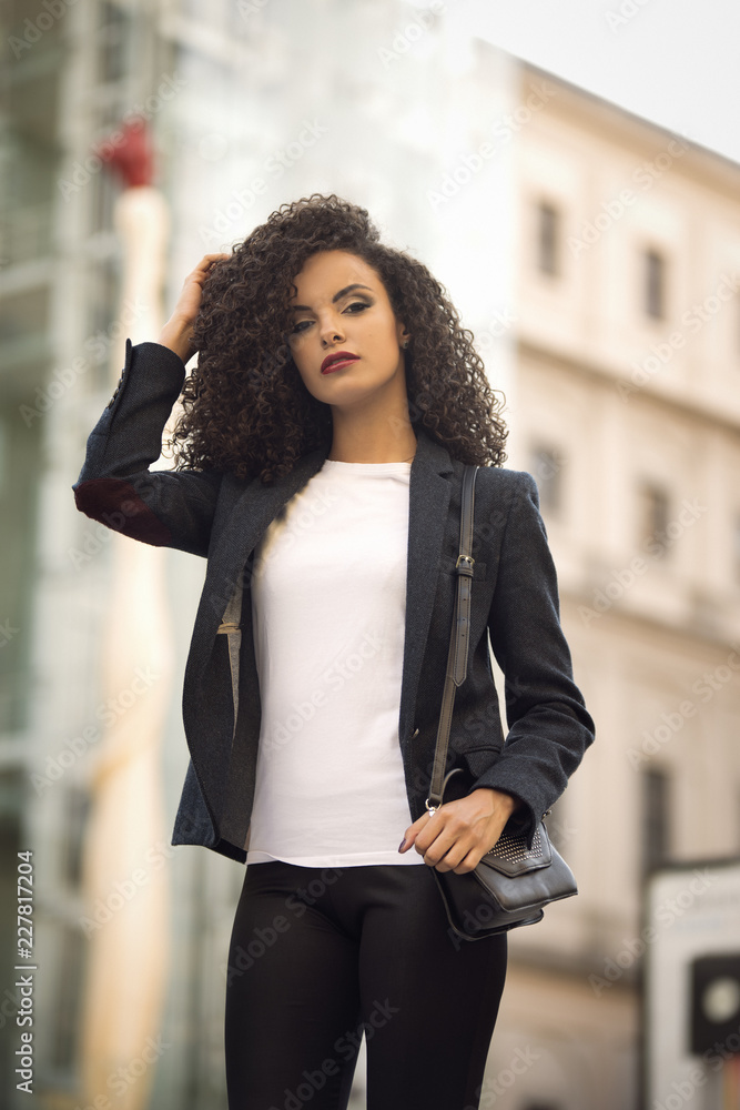 Beauty girl with curly hair in street looking at camera