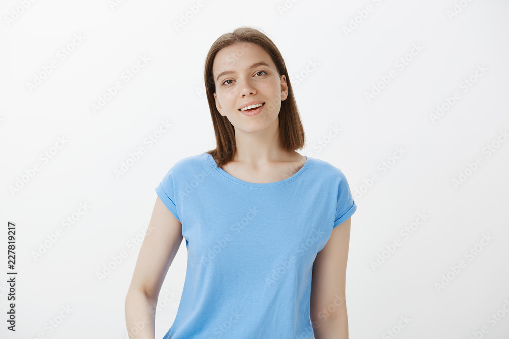 Charmed attractive cute girl with fair hair and clean skin, gazing fascinated at camera and smiling broadly, being like in dream after seeing love of her life, standing pleased over grey wall Charmed attractive cute girl with fair hair and clean skin, gazing fascinated at camera and smiling broadly, being like in dream after seeing love of her life, standing pleased over grey wall