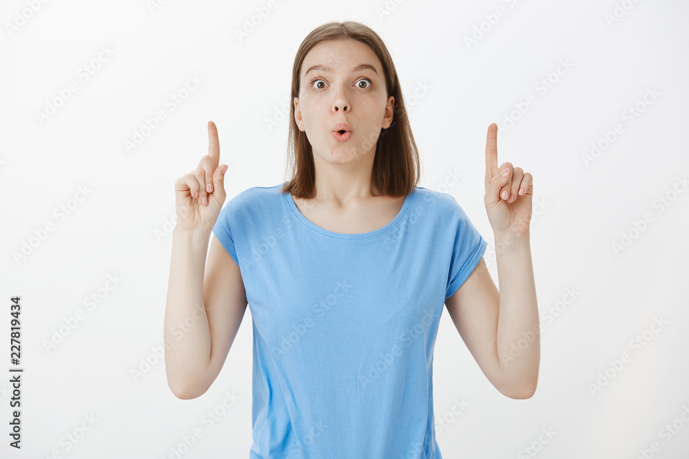 Excited joyful woman with tattoos on arms, saying eureka and raising index fingers while having great plan or idea, finding solution or answer on question, standing relieved over grey wall Excited joyful woman with tattoos on arms, saying eureka and raising index fingers while having great plan or idea, finding solution or answer on question, standing relieved over grey wall