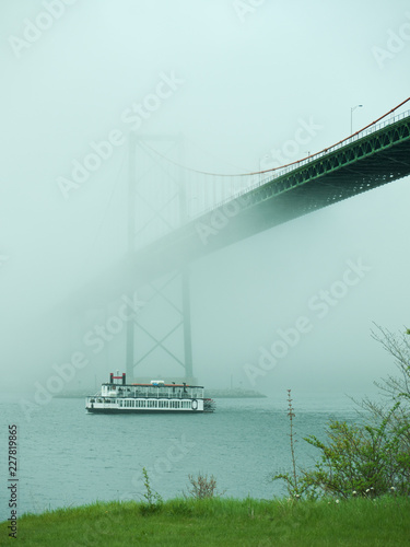Ferry boat crossing under a suspension bridge in Halifax, Nova Scotia in thick fog. 