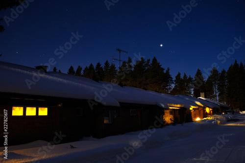 Row house in snowy winter night. Planet Venus and The Pleiades in starry sky.