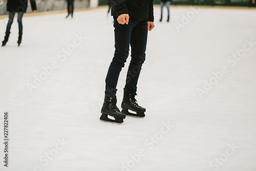 Skaters skating on iceskating ring in european city center in winter holidays. Kids playing on white ice skating ring, healthy activity. Child legs in black skates