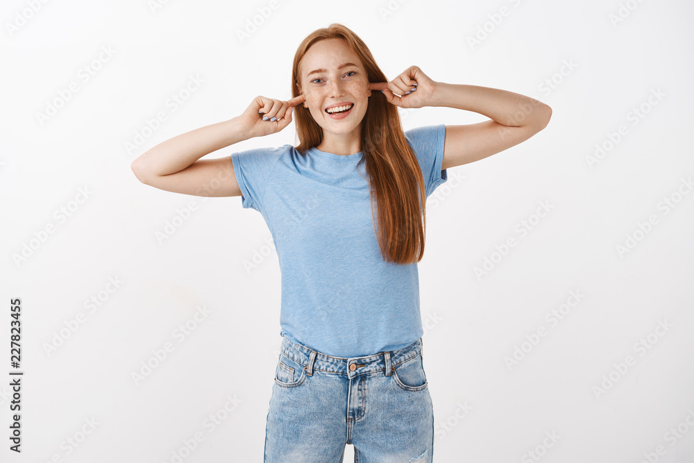 Cannot hear what you say. Portrait of playful carefree and optimistic charming redhead female with freckles closing ears with index fingers and smiling from joy avoiding arguing over gray background Cannot hear what you say. Portrait of playful carefree and optimistic charming redhead female with freckles closing ears with index fingers and smiling from joy avoiding arguing over gray background