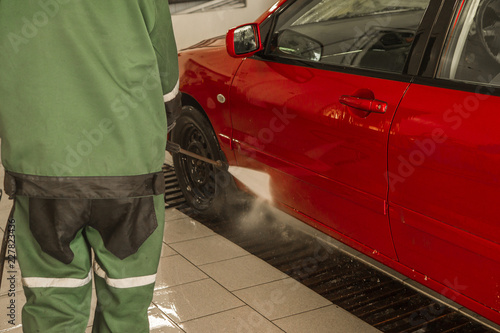 Red passenger car in the box at the car wash. Integrated washing under the pressure of water. © Дмитрий Федоров