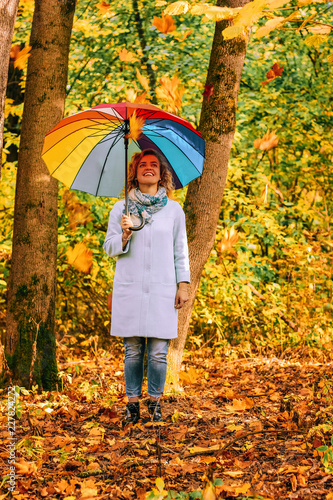 Young beautiful girl walks in the autumn park with a colorful umbrella © volhavasilevich