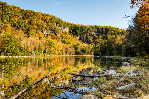 Fototapeta Naklejka Na Ścianę i Meble -  Mountain and colorful trees reflected in a pond on a beautiful autumn day