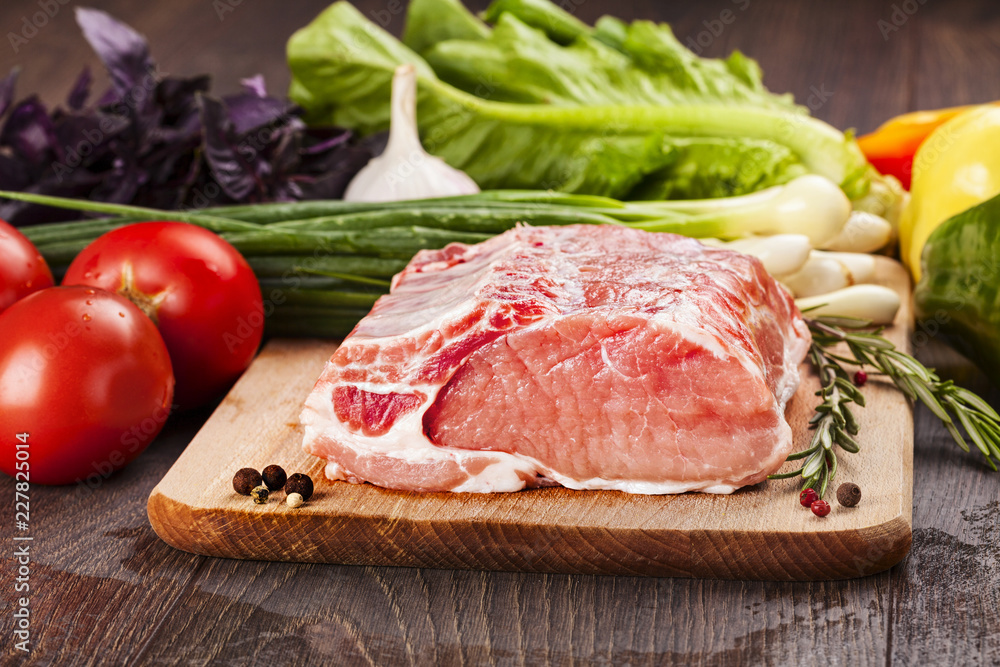 Raw pork for cooking and  barbecue on cutting board with vegetables.