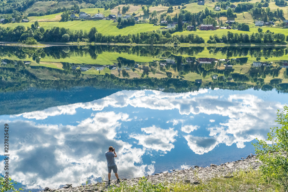 Photographer standing on the shore of the mountain lake in Norway