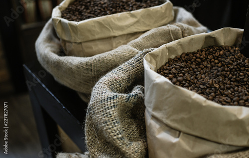 Big vintage brown coffee bags with black roasted beans on the table. Cafe interior decorations. Closeup © Yurii Zymovin