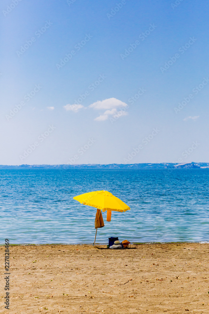 Yellow umbrella on beach by lake