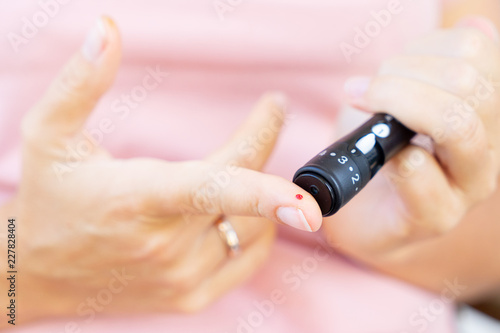 close up of someones hands measuring blood sugar level, world diabetes day concept