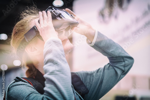 Young girl enjoying virtual reality glasses in high tech exchibition photo