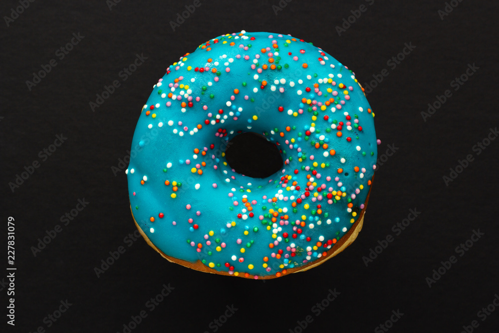 Donut blue with sprinkles isolated on black background, close-up Donut blue with sprinkles isolated on black background, close-up