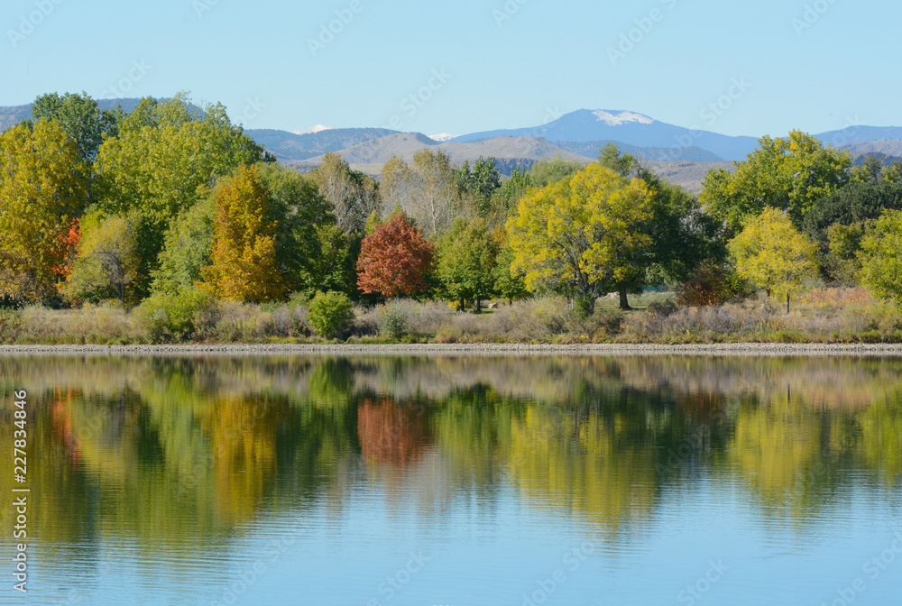 Colorado lake landscape with autumn trees with reflection and view of snow on Rocky Mountain foothills in background Colorado lake landscape with autumn trees with reflection and view of snow on Rocky Mountain foothills in background