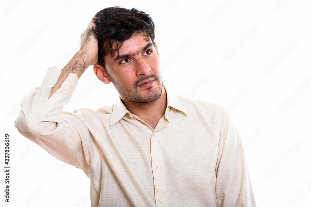 Studio shot of young Persian businessman thinking while brushing Studio shot of young Persian businessman thinking while brushing