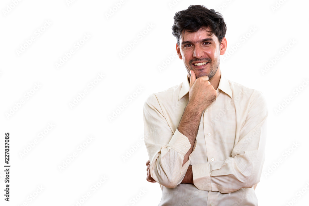 Studio shot of young happy Persian businessman smiling while thi Studio shot of young happy Persian businessman smiling while thi