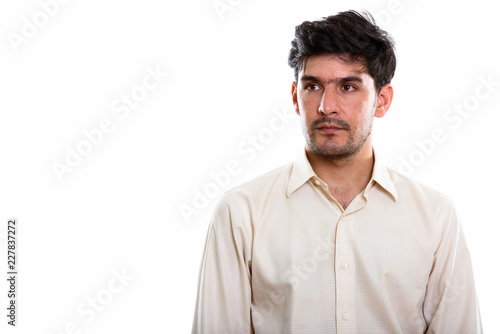 Studio shot of young Persian businessman thinking while looking 